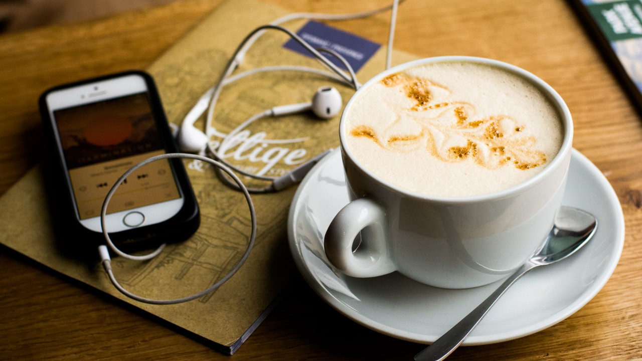 Kaffee mit Smartphone und Kopfhörern auf dem Tisch